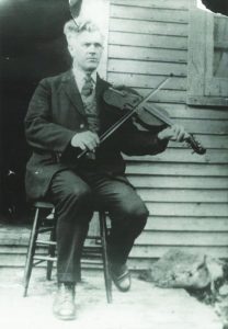 Joseph Allard qui joue du violon sur un perron 
