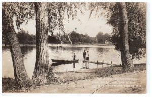 deux personnes sur un quai et une dans une chaloupe sur la rivière