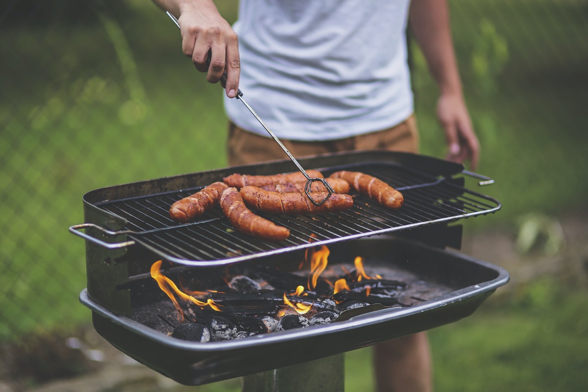Un homme qui cuit des saucisses sur un barbecue